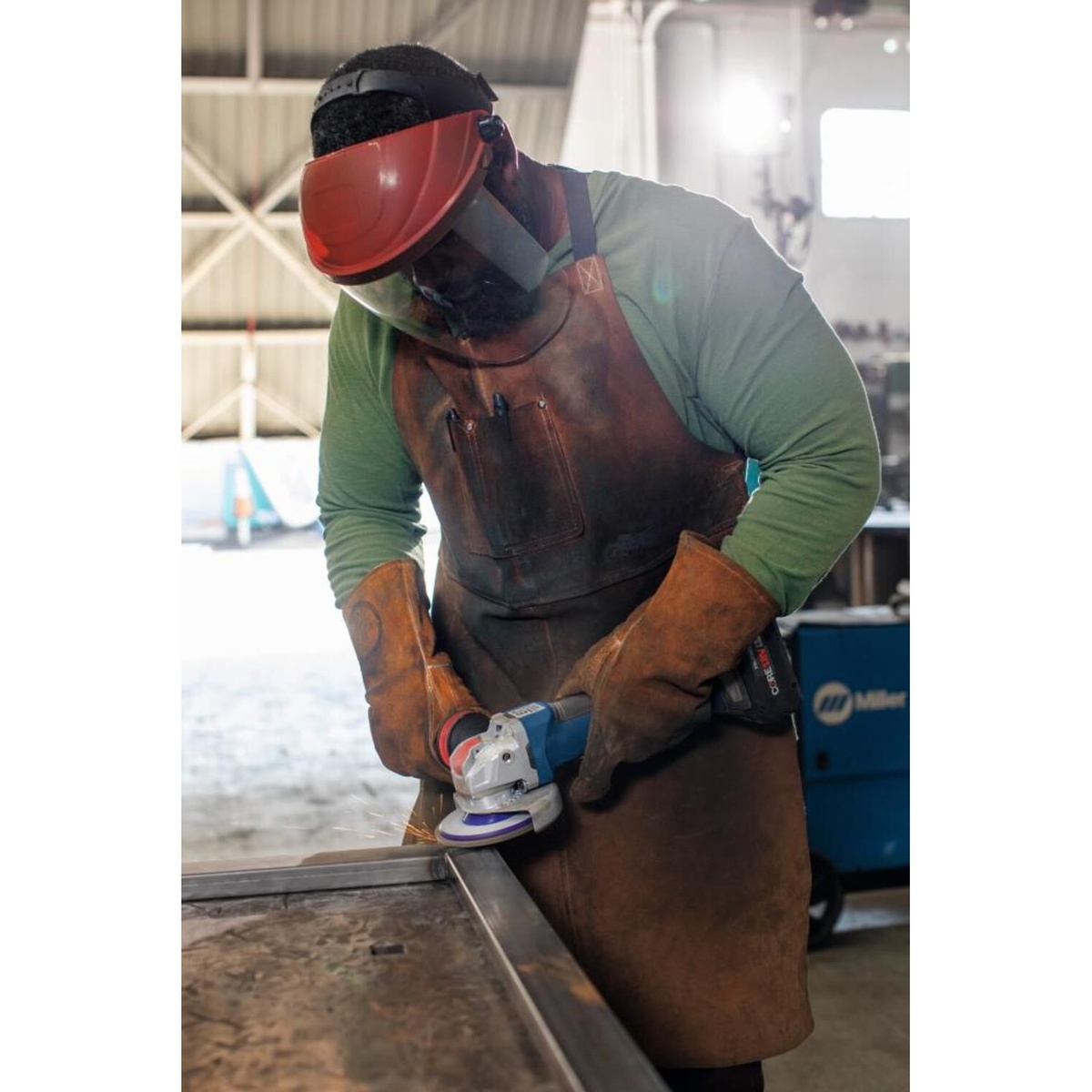 Bosch X LOCK Arbor Type 29 40 Grit Flap Disc 4 1/2in grinding steel tubing with a small angle grinder in a metalworking shop