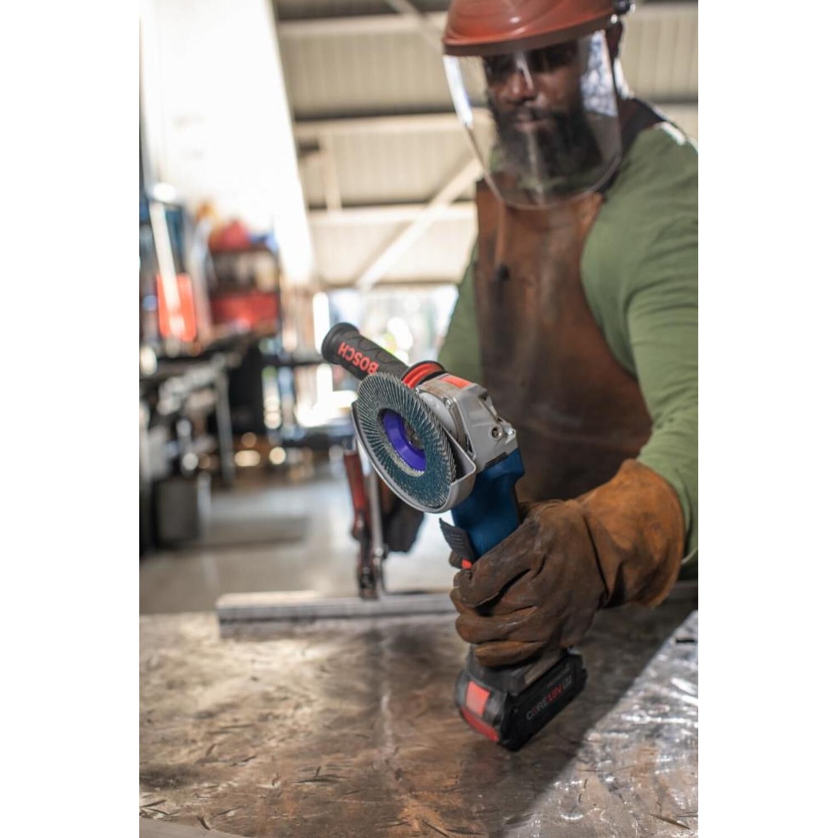 Bosch X LOCK Arbor Type 29 40 Grit Flap Disc 4 1/2in mounted on a cordless grinder for metal blending work at a fabrication table