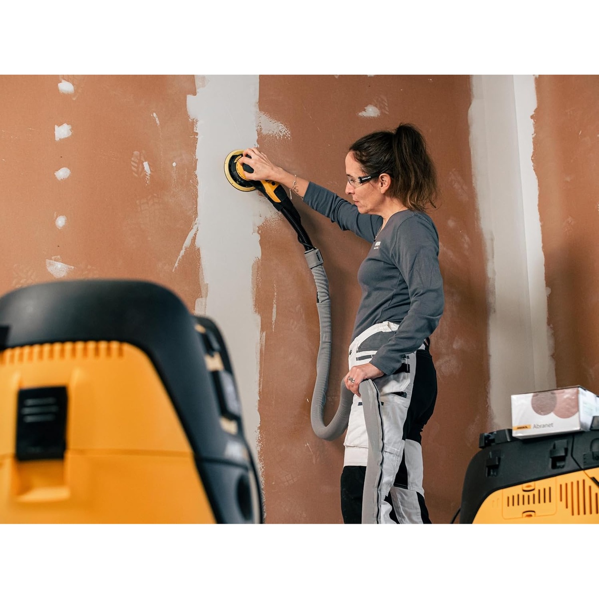 Mirka DEROS 650X CV random orbital sander sanding drywall compound on an interior wall with dust extraction connected during surface prep work