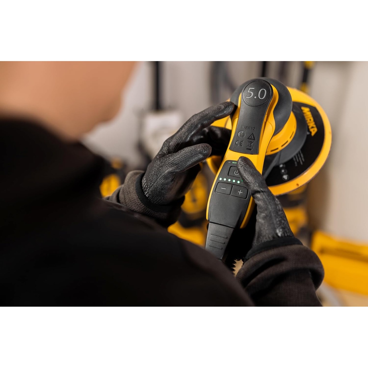 Mirka DEROS II 750X 7 in Random Orbital Sander being adjusted by a gloved user in a workshop before large surface sanding work