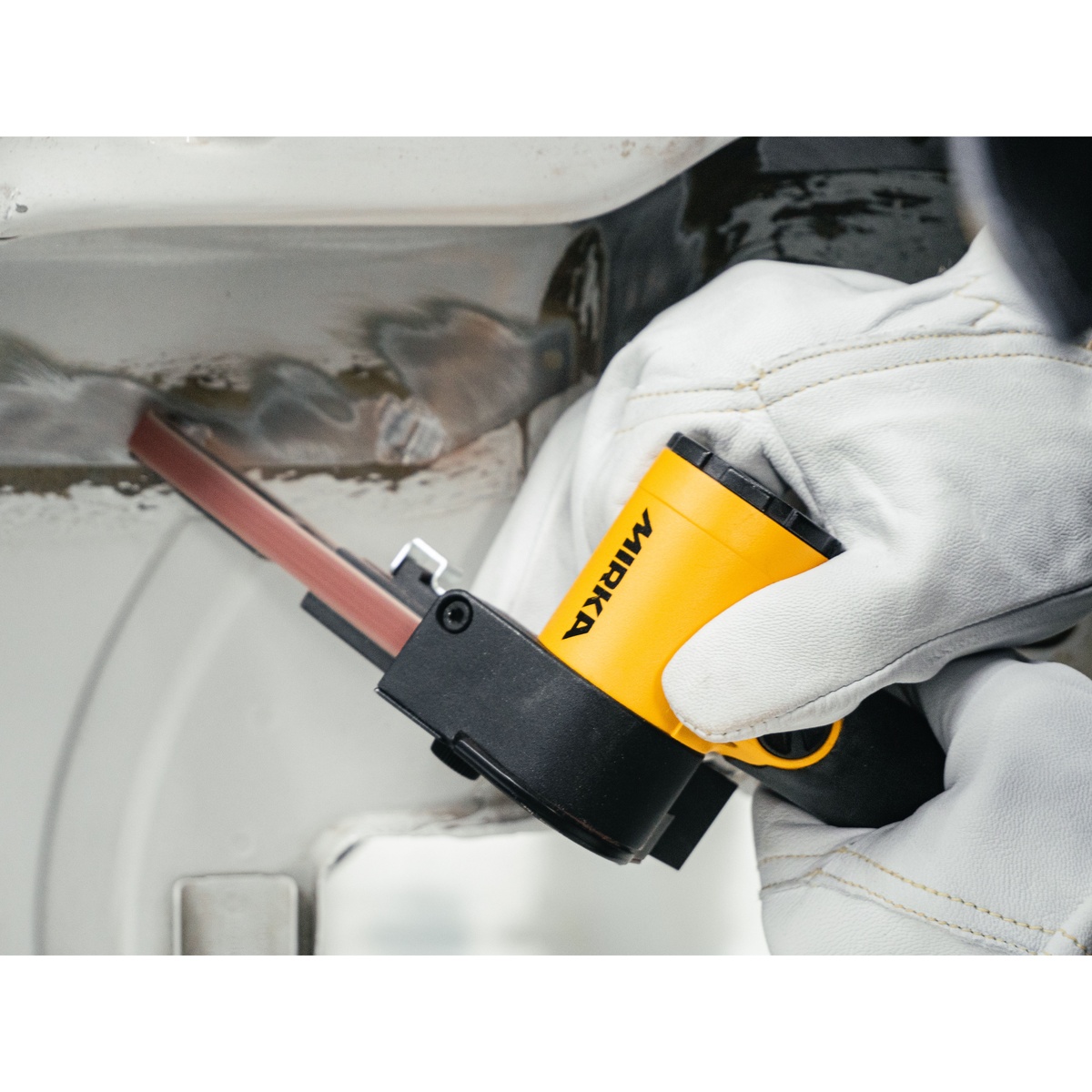Mirka PBS-10330 Pneumatic Belt Sander sanding a metal automotive panel weld seam in a tight bodywork repair area