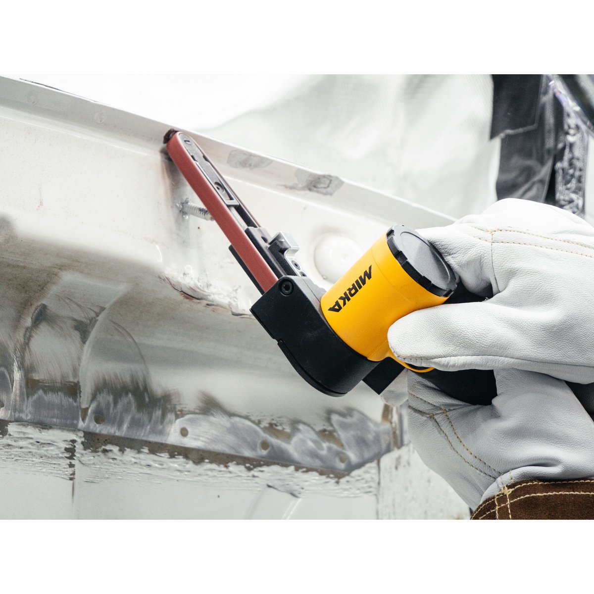 Mirka PBS-10330 Pneumatic Belt Sander working along a metal edge for weld cleanup and surface preparation in auto body repair