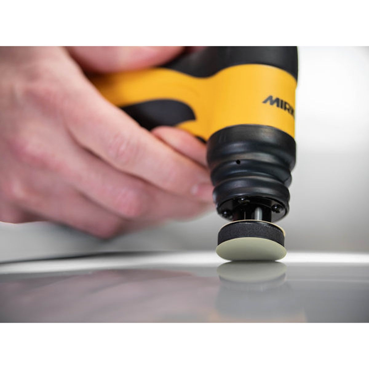 Mirka Iridium SR 1.25 inch diameter PSA abrasive disc used with a Mirka cordless detail sander on an automotive painted panel during spot finishing