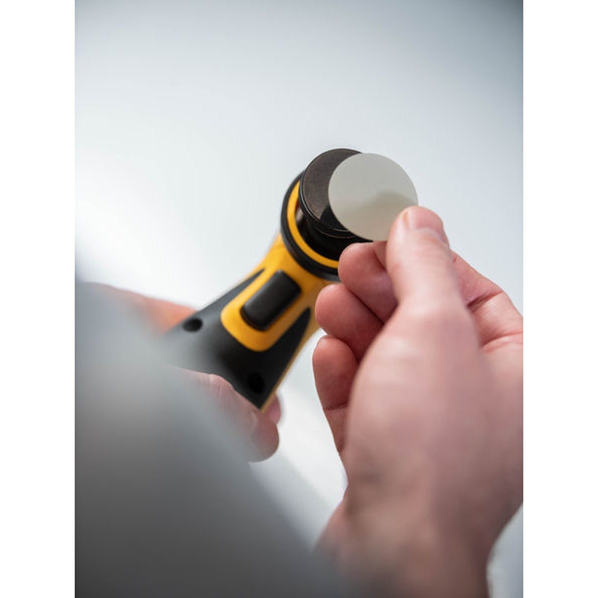 Mirka Iridium SR 1.25 inch diameter PSA abrasive disc being mounted onto a Mirka cordless sander backing pad for detail finishing work