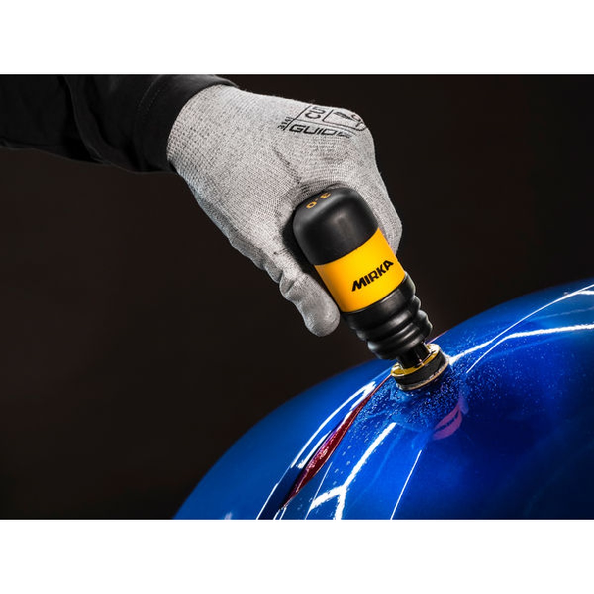 Mirka Iridium SR 1.25 inch diameter PSA abrasive disc sanding a curved automotive panel during collision repair finishing