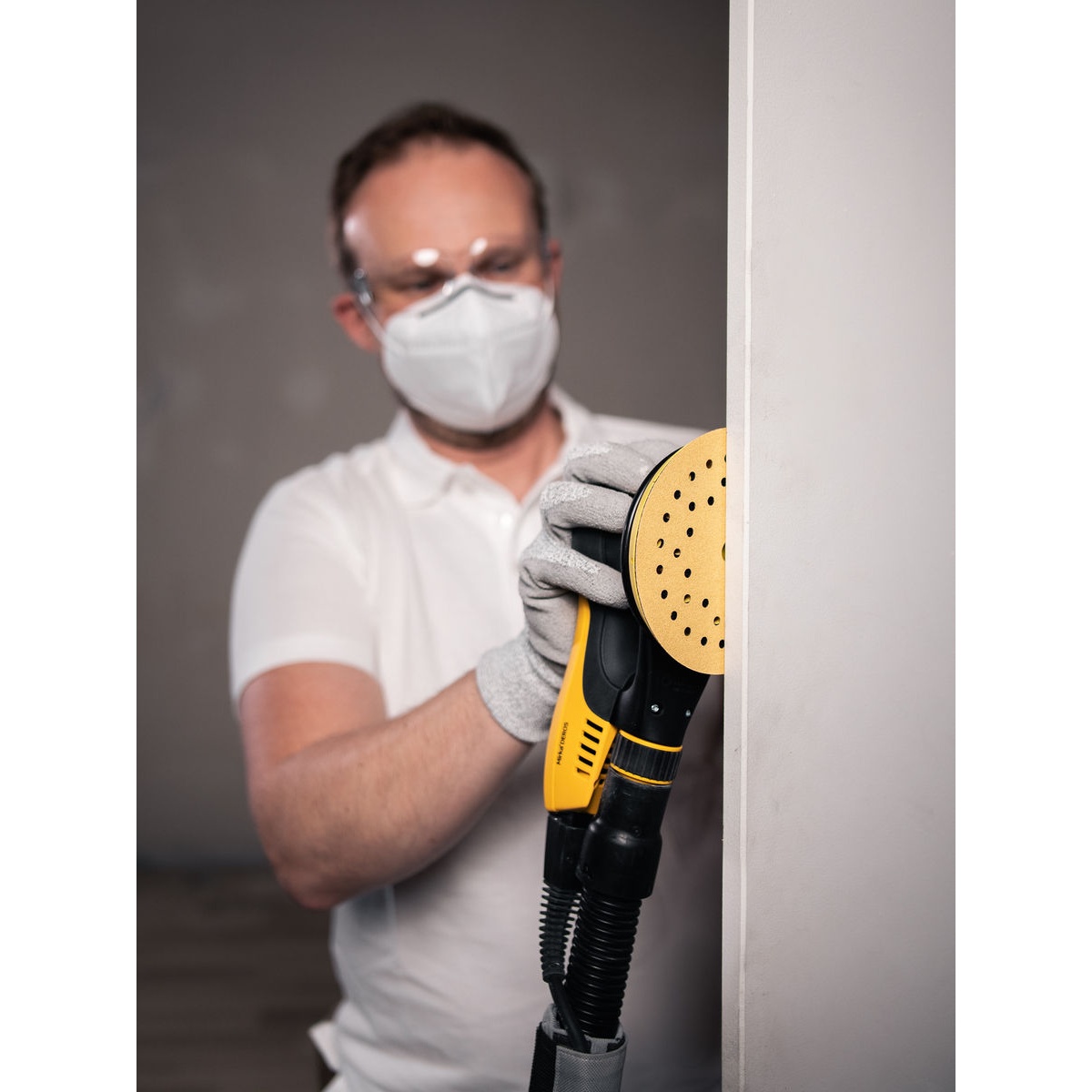 Mirka GOLD Multifit 6 inch Grip P40 sanding disc used on an orbital sander for edge sanding on an interior wall surface