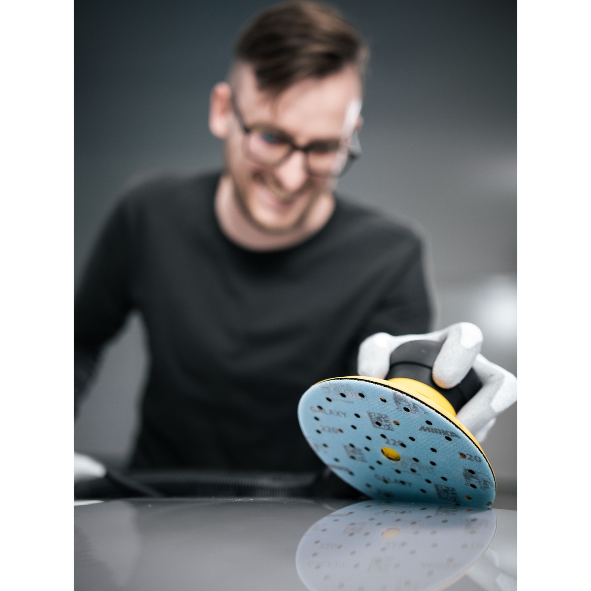 Mirka GALAXY sanding disc used on a surface with a random orbital sander during finishing work in a workshop