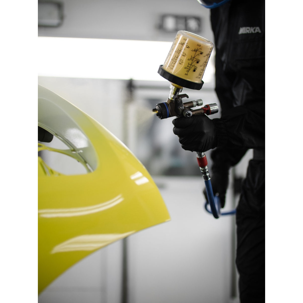 Mirka Paint Cup System with 125µm Filter Lid 400ml attached to a spray gun during automotive refinishing on a painted body panel
