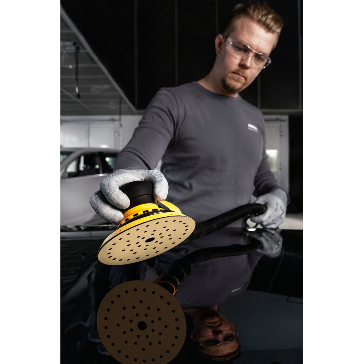 Mirka GOLD Multifit 5 in Grip Sanding Discs installed on a dust-extracted orbital sander during automotive surface preparation on a painted panel