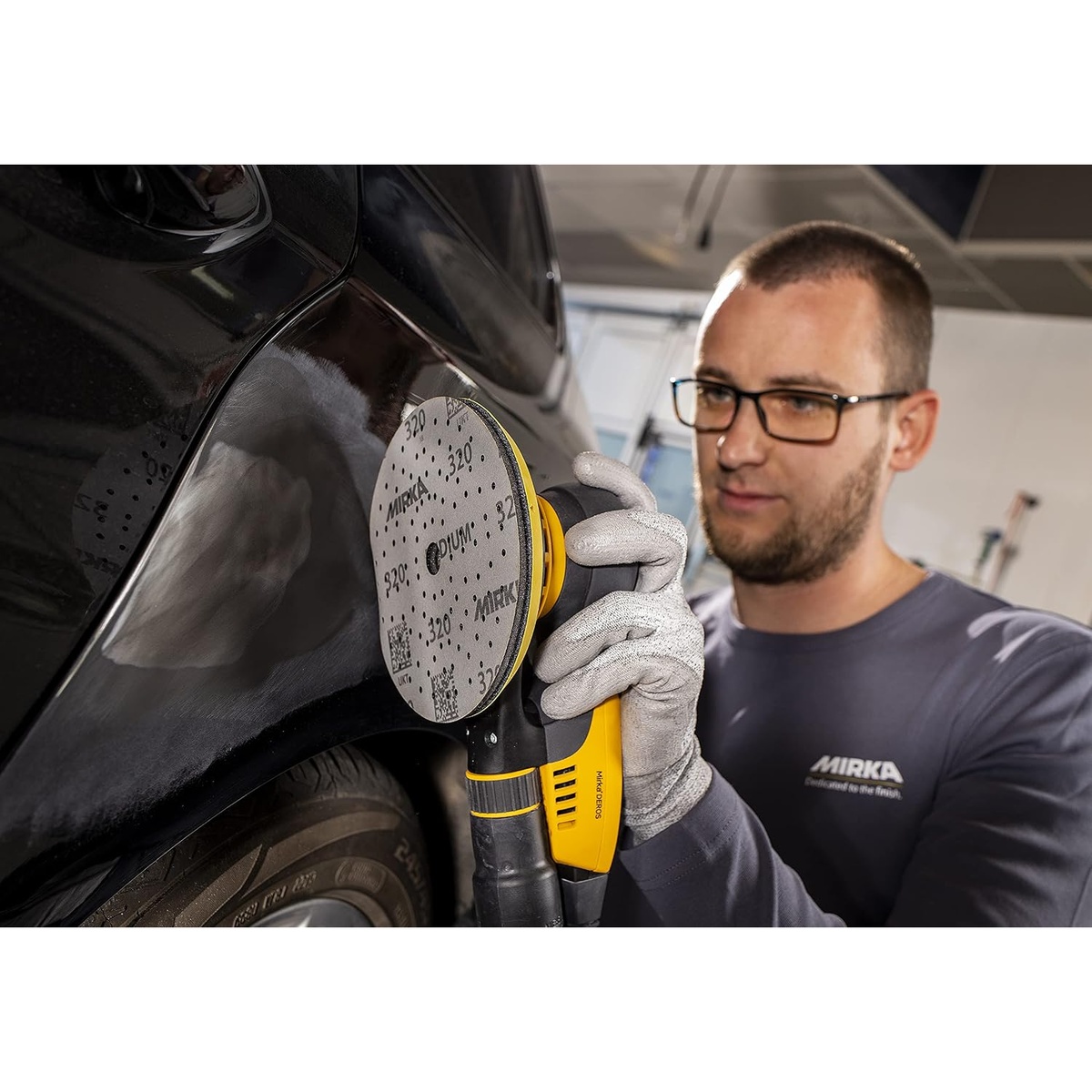 Mirka Iridium 5-Inch Sandpaper Discs used on a random orbital sander for automotive body sanding on a vehicle panel during surface preparation