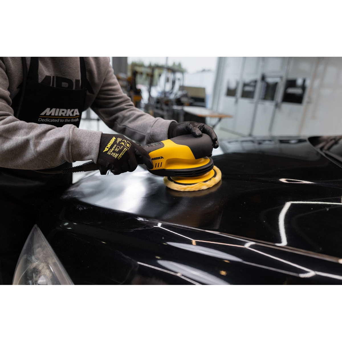 Mirka POLAROS RP 600X 6 inch rotary polisher polishing a black automotive panel during paint correction in a professional shop