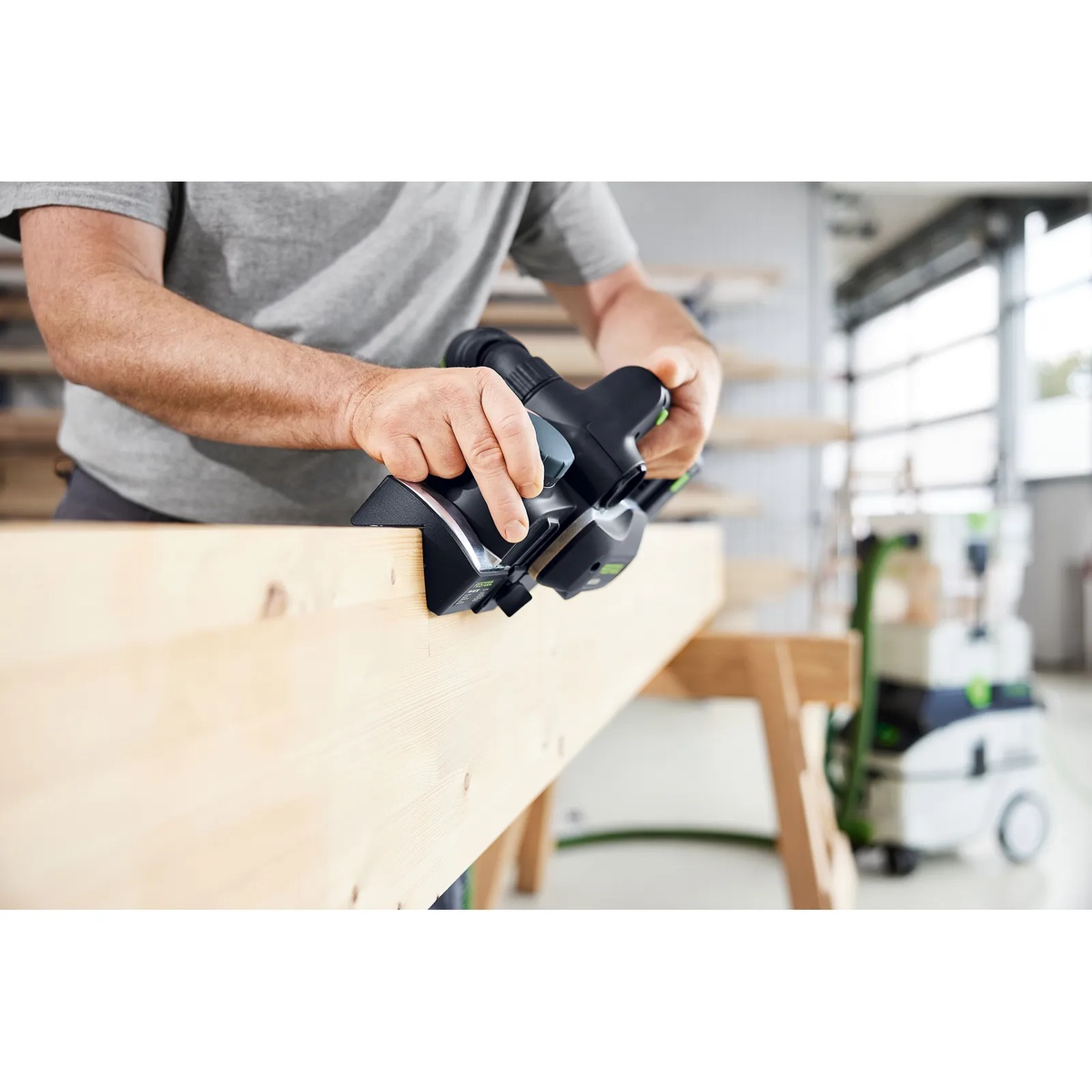 Festool FNS-HLC 82 chamfer adaptor installed on an HLC 82 cordless planer creating a chamfer on a wood beam in a workshop setting