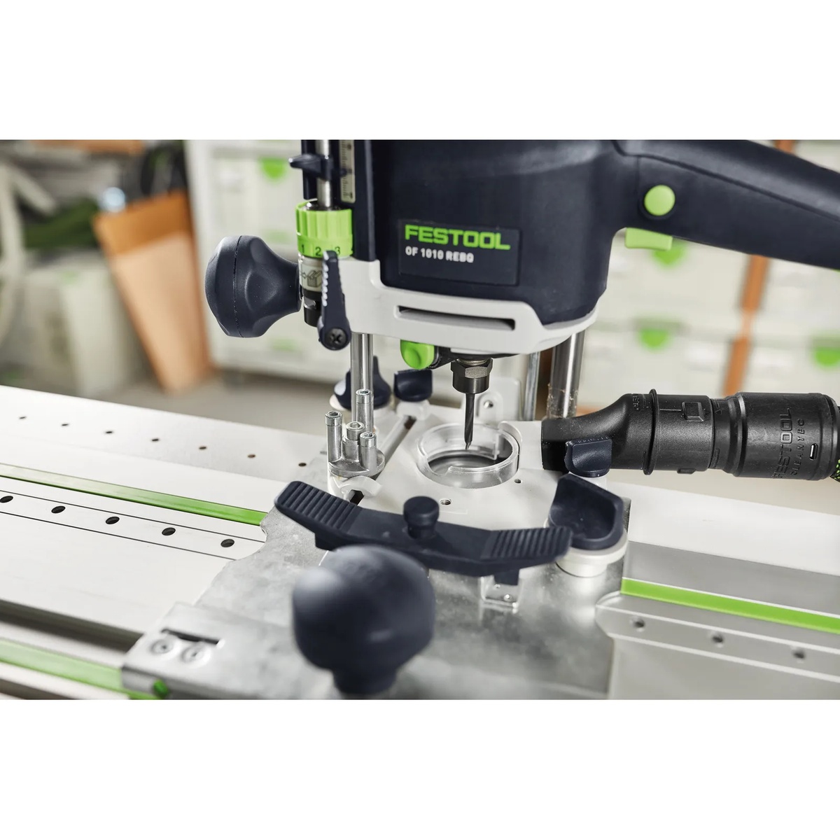 Close-up of a Festool router mounted to the Festool FS1400/2-LR 32 guide rail with dust extraction attached during precise hole drilling on a cabinet panel