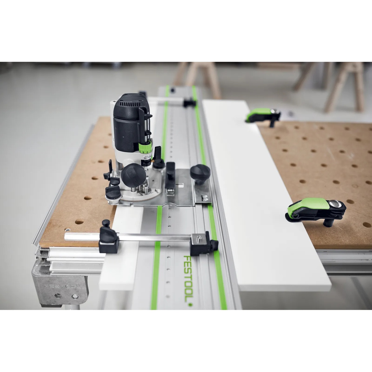 Festool LR 32 hole drilling set mounted to a router on a guide rail over a white cabinet panel, showing portable line boring setup for cabinet installation and shop work