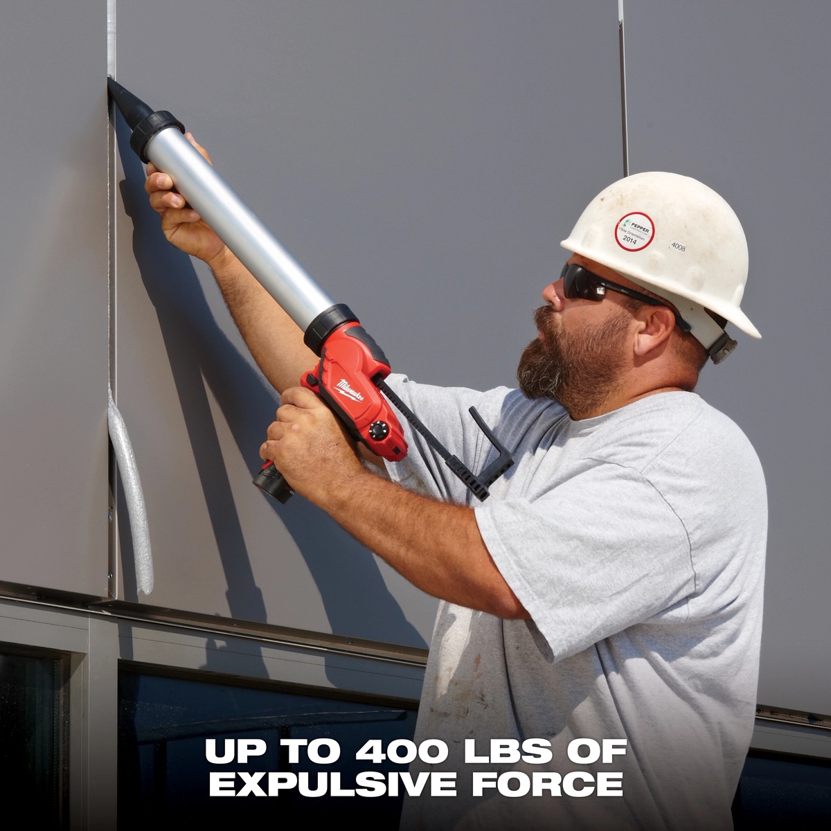 Milwaukee 2441-20 M12 10 oz caulk and adhesive gun dispensing material upward on an exterior wall seam during commercial sealing work