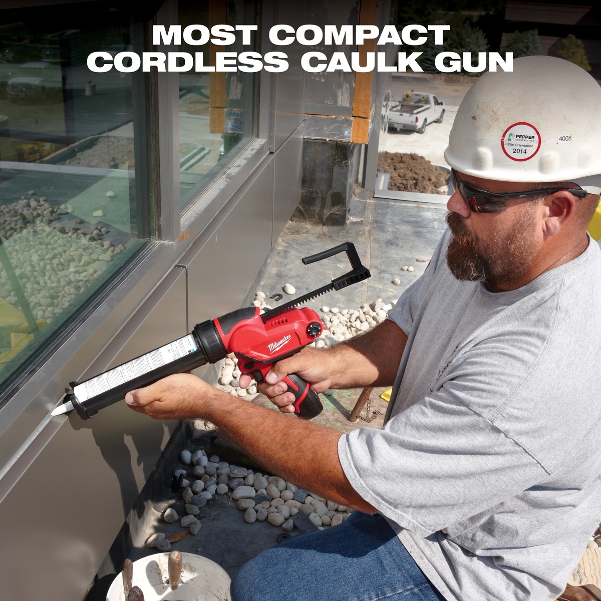 Milwaukee 2441-20 M12 10 oz caulk and adhesive gun applying sealant along an exterior metal building seam on a jobsite