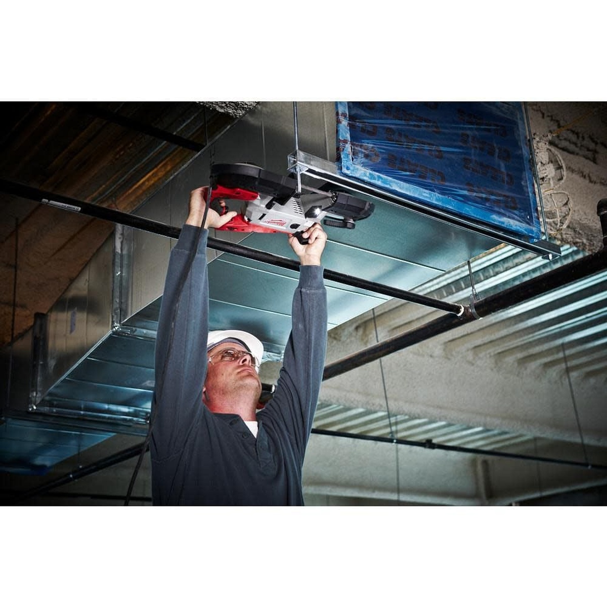 Milwaukee Deep Cut Variable Speed Band Saw Kit being used overhead to cut metal support material near HVAC ductwork on a jobsite