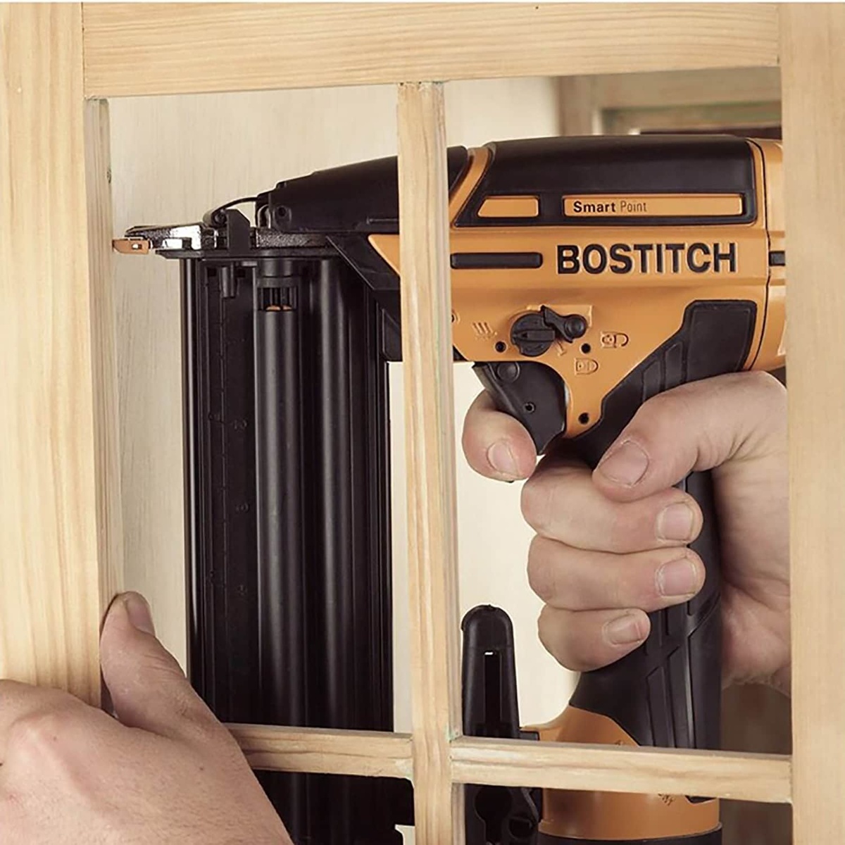 Bostitch BTFP12233 Smart Point 18 Gauge Brad Nailer Kit driving brad nails into narrow wood trim inside a tight cabinet-style frame during finish carpentry work