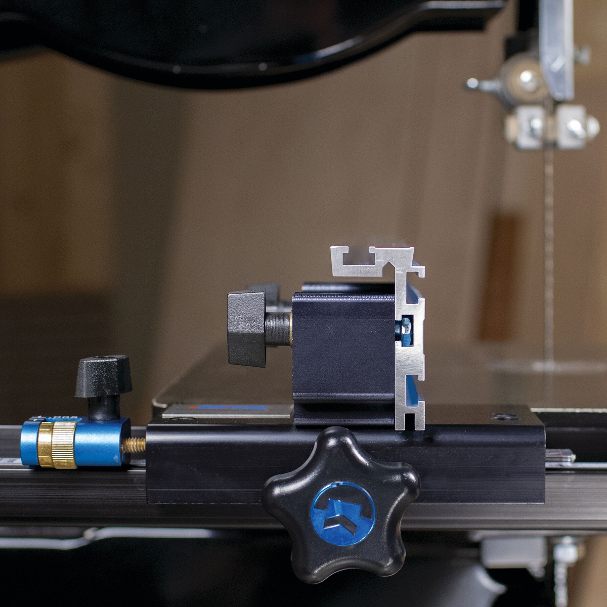 Close-up of the Kreg Tool KMS7200 Precision Band Saw Fence locking mechanism and fence profile on a band saw in a woodworking shop