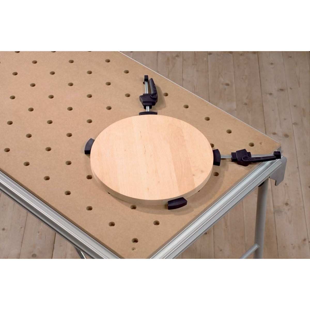 Festool clamping elements holding a round wood panel on an MFT table for edge work and sanding