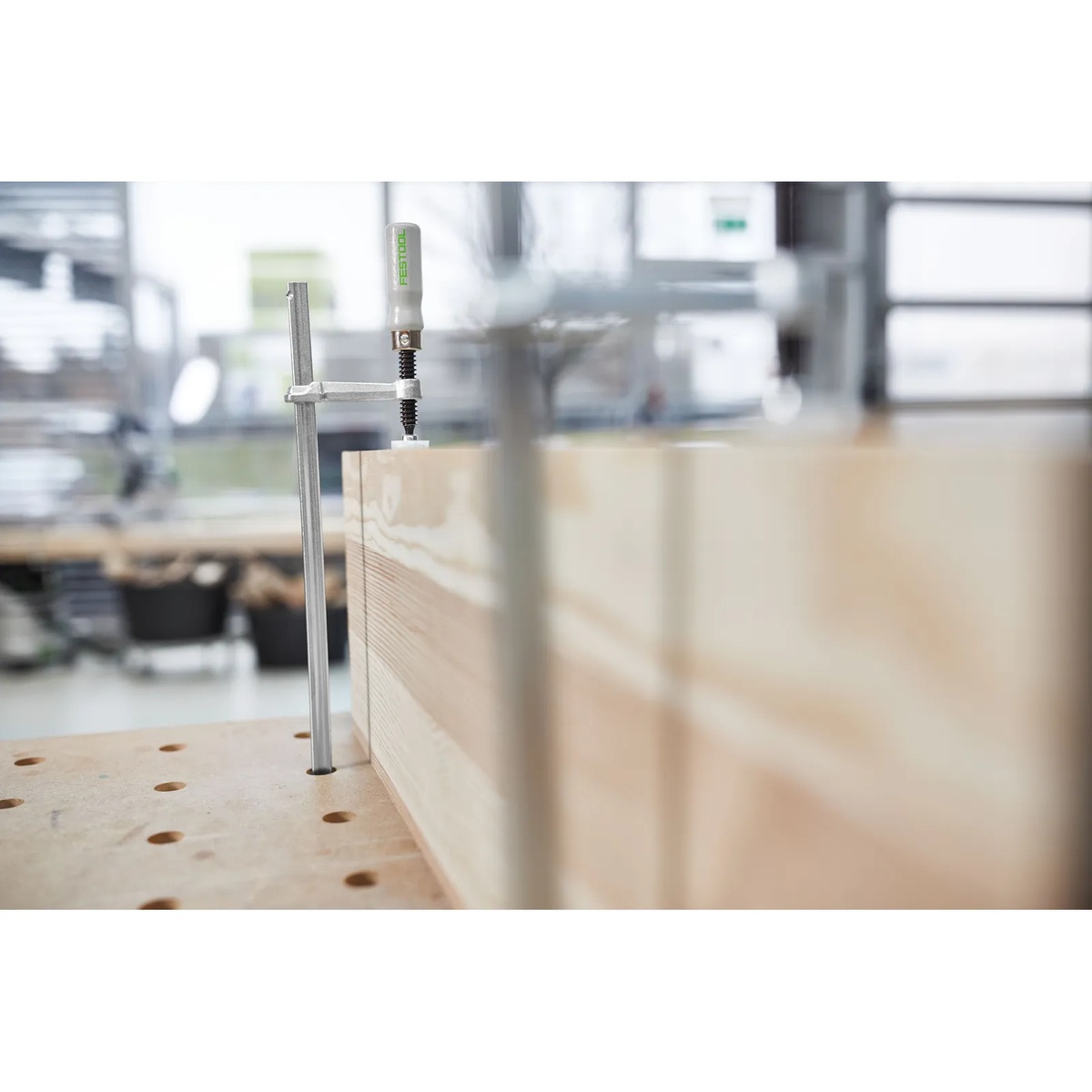 Festool FSZ 300 Screw Clamps holding a long wood board on a perforated worktable during guide rail and bench-top woodworking