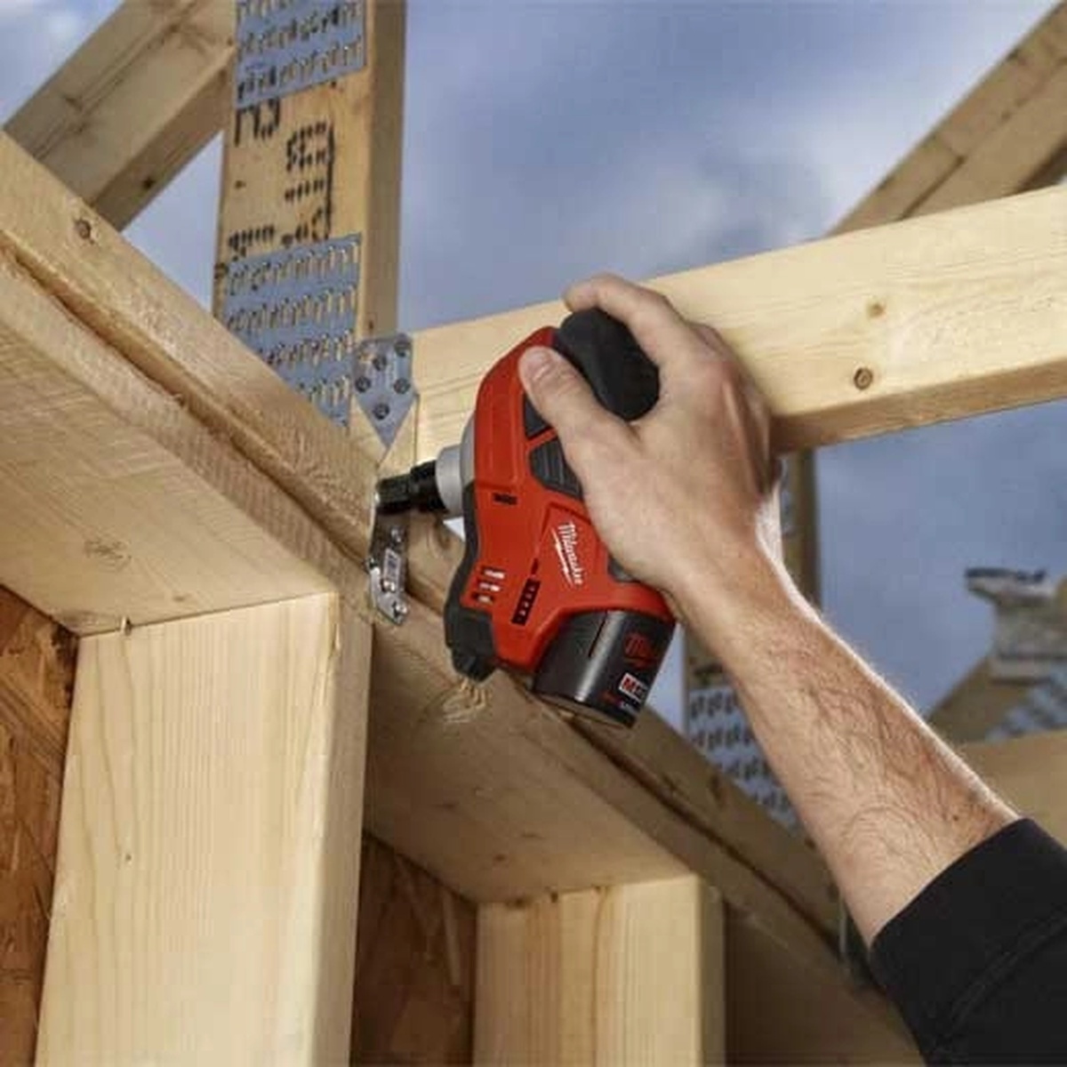 Milwaukee 2458-20 M12 Cordless Palm Nailer fastening framing hardware with one-handed use on wood framing at a jobsite