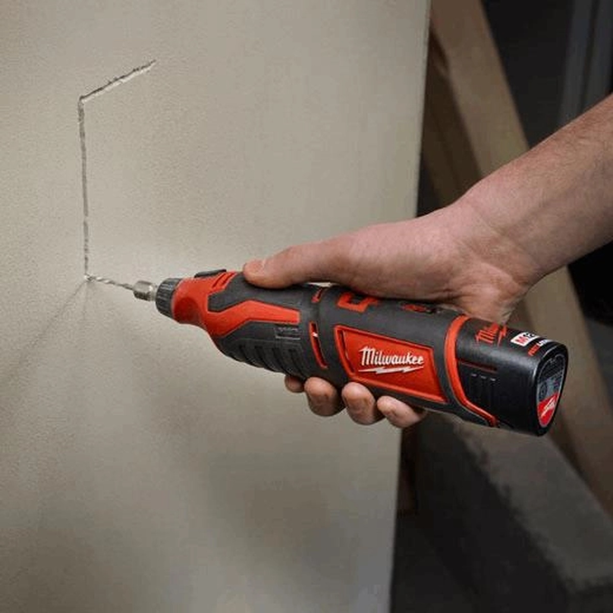 Milwaukee M12 Cordless Lithium-Ion Rotary Tool cutting into wall material during detail work in a tight indoor remodeling setting
