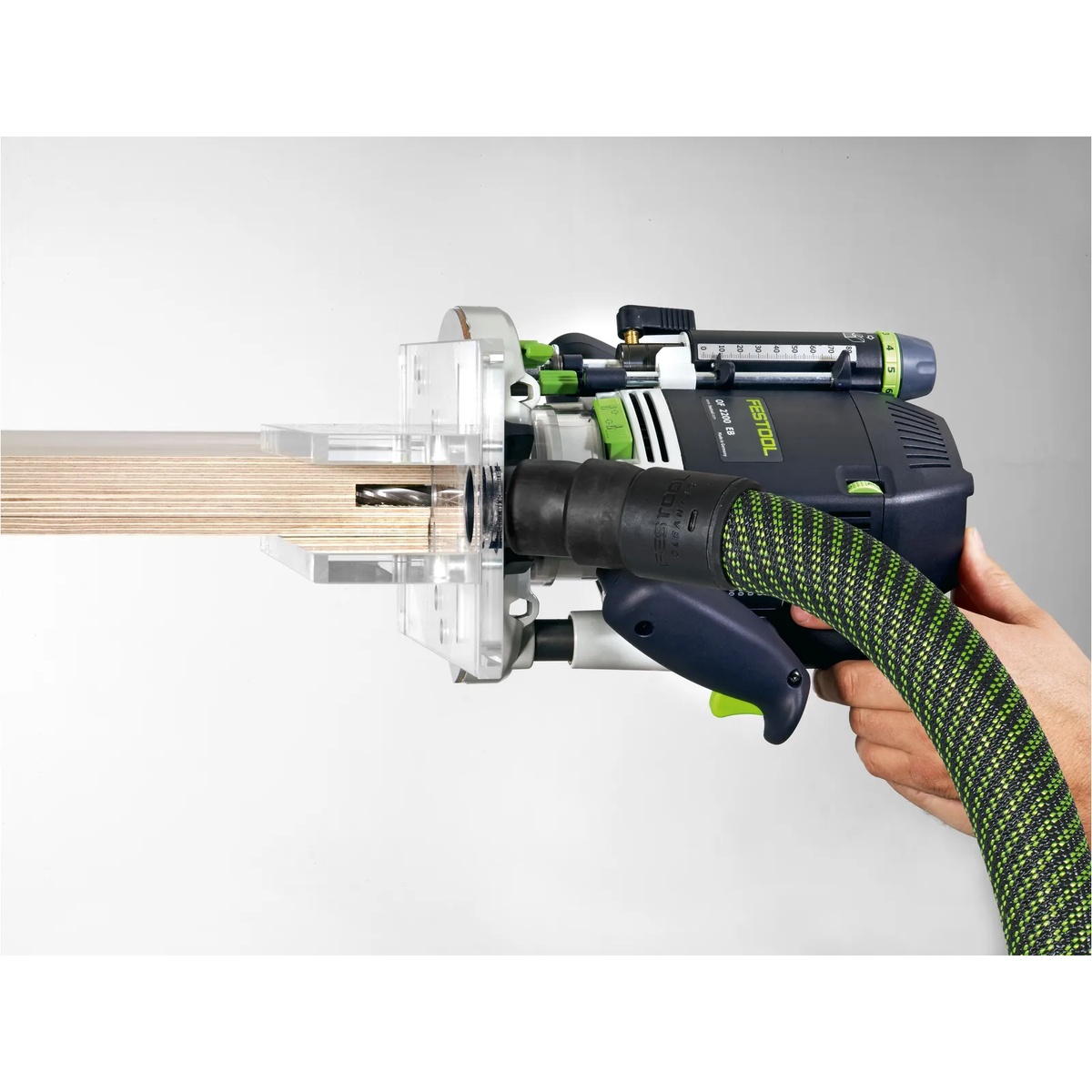 Festool OF-FH 2200 Routing Aid attached to a Festool router cutting a groove in the edge of plywood with dust extraction hose connected for cleaner routing