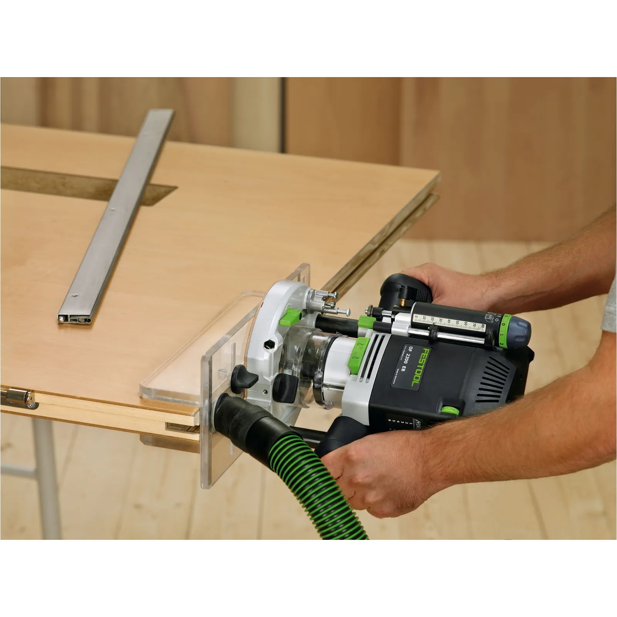 Festool OF-FH 2200 Routing Aid being used with a Festool router on the edge of a door or panel for precise groove routing in a woodworking shop