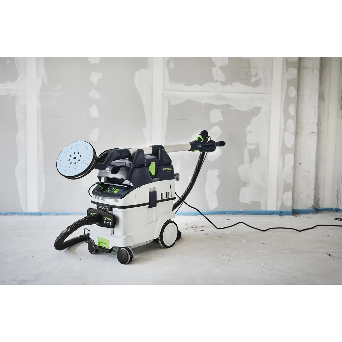 Festool 577101 CT AutoClean Antistatic Hose attached to a PLANEX drywall sander and dust extractor in a drywall finishing room with patched wall surfaces