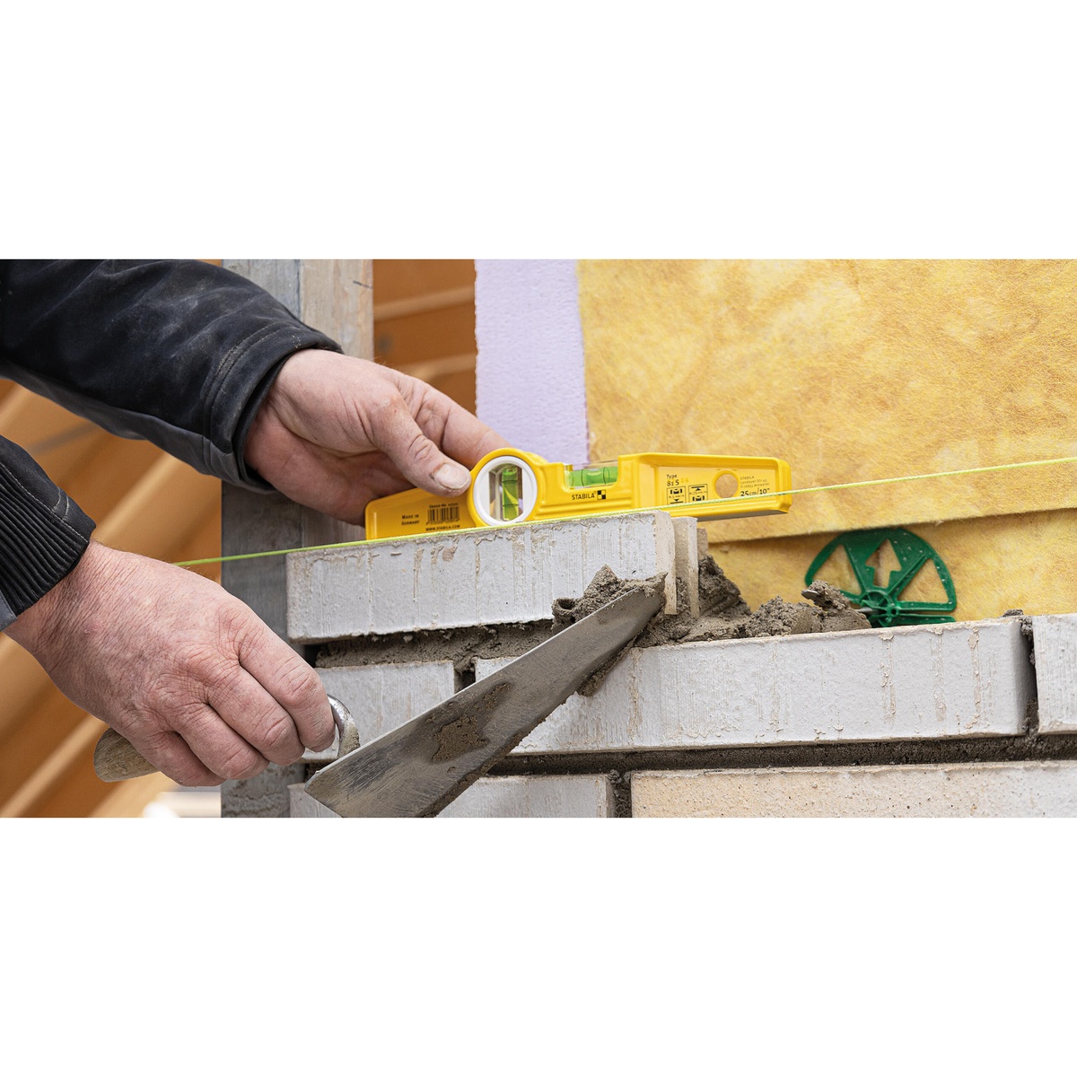 Stabila 25010 Die Cast Torpedo Level on brickwork beside a mason line showing horizontal leveling accuracy during wall layout