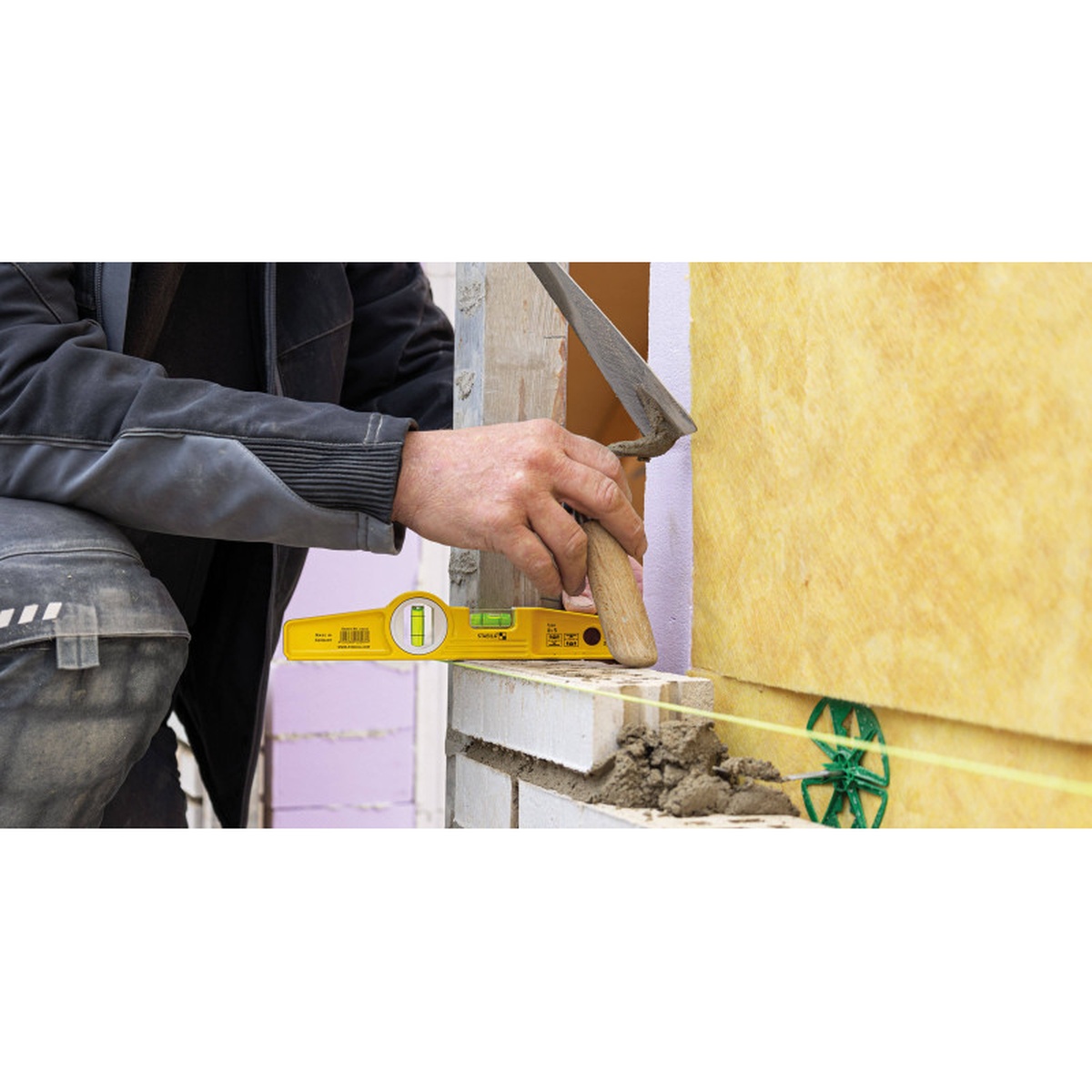 Stabila 25010 Die Cast Torpedo Level checking level on a masonry wall during brick installation on a real jobsite