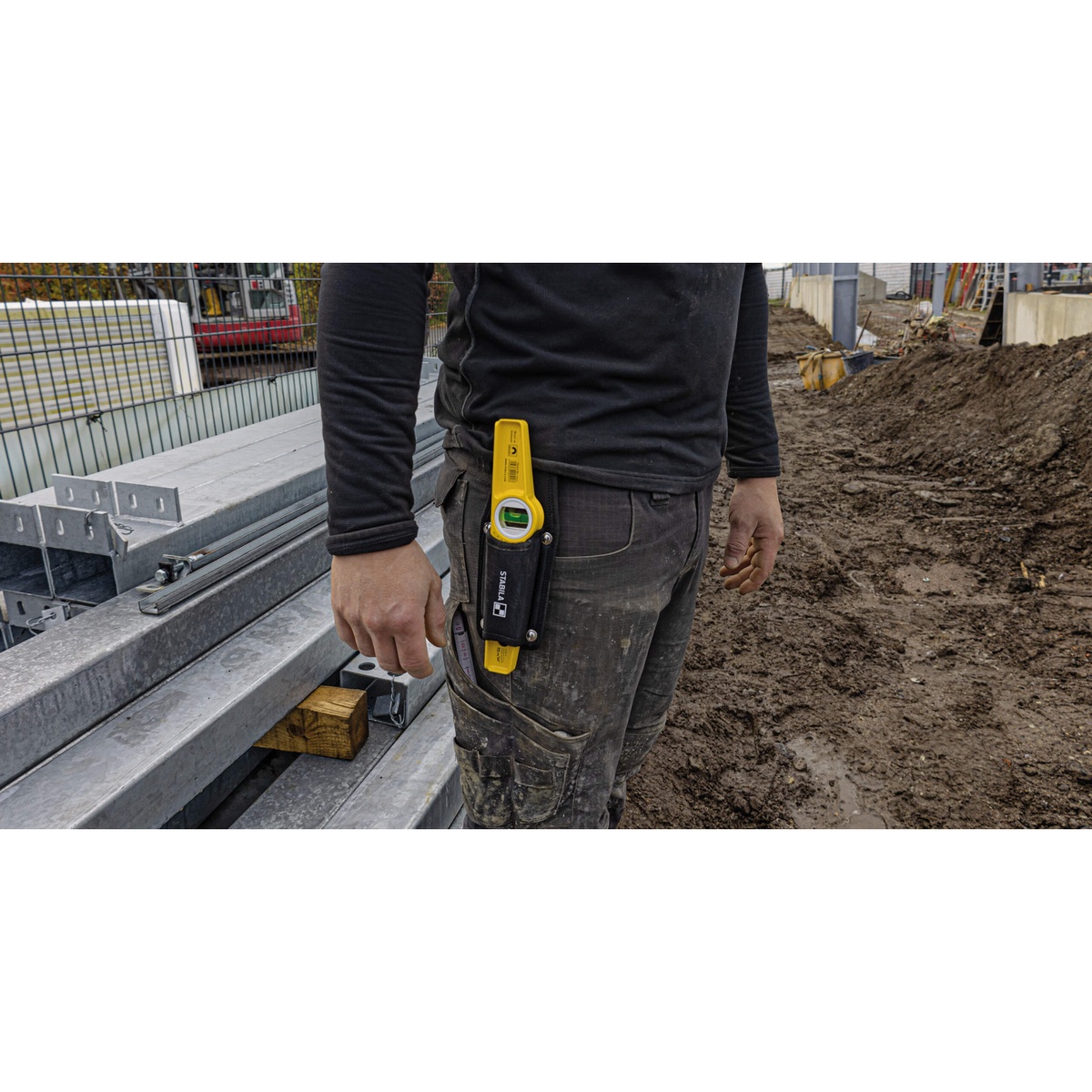 Stabila Type 81SM Die Cast Magnetic Torpedo Level carried on a jobsite during steel framing work with metal components and muddy construction conditions