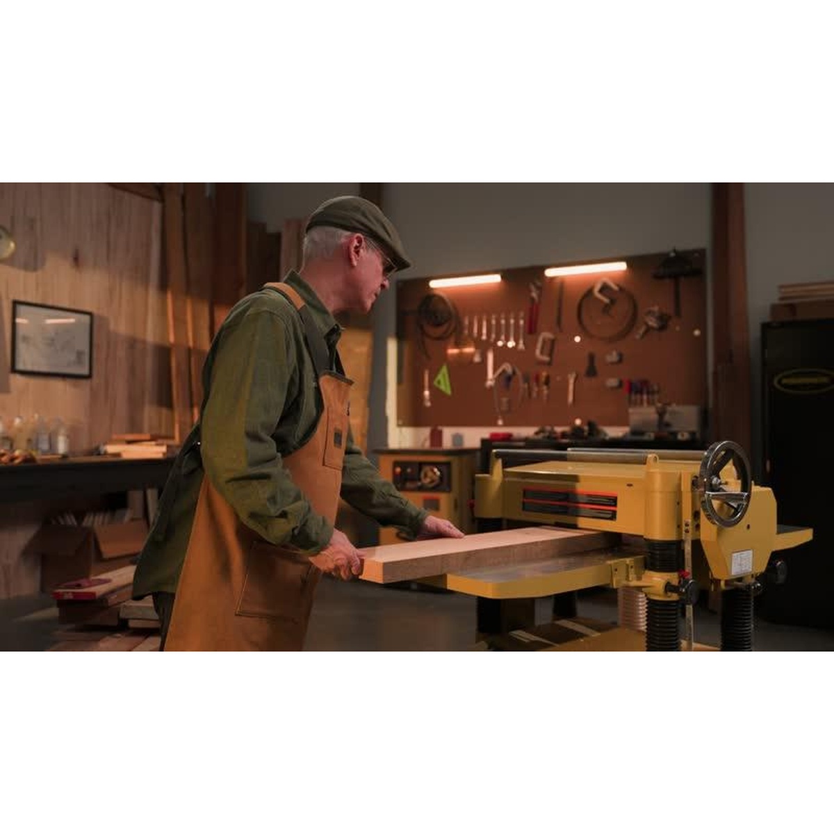 Powermatic 209HH 20-Inch Planer feeding a thick wood board in a cabinet shop during stock preparation and finish planing