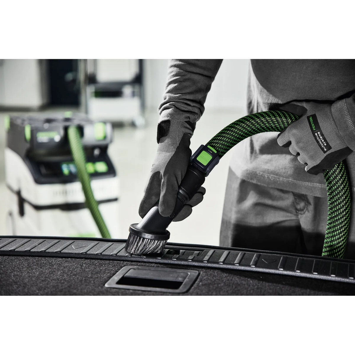 Festool 440404 Suction Brush connected to a Festool hose while cleaning a textured vehicle cargo surface in a real-world detail and cleanup application