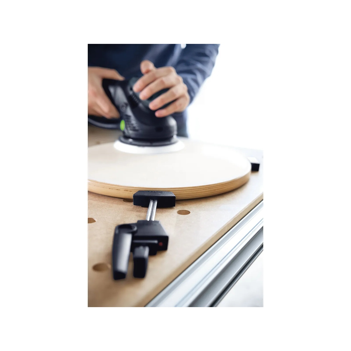 Festool 500608 Multifunction Table MFT/3 Basic holding a round wood panel while a sander is used for finish sanding on a bench surface in a workshop