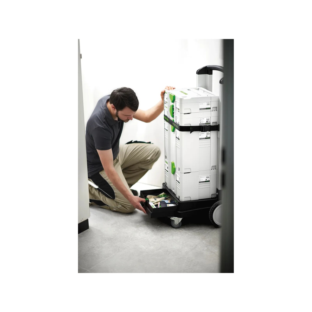 Festool 498660 Sys-Roll Systainer Cart holding stacked Festool Systainers in a real indoor jobsite hallway while a user opens the drawer for small parts access