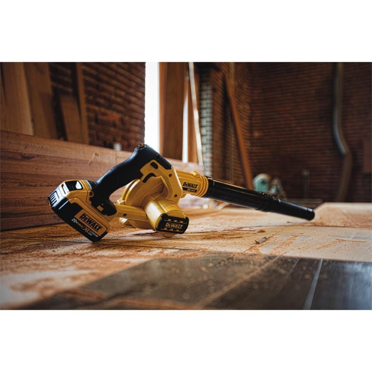 DEWALT DCE100B 20V MAX Compact Jobsite Blower resting on a dusty wood floor during indoor jobsite cleanup in a remodeling space
