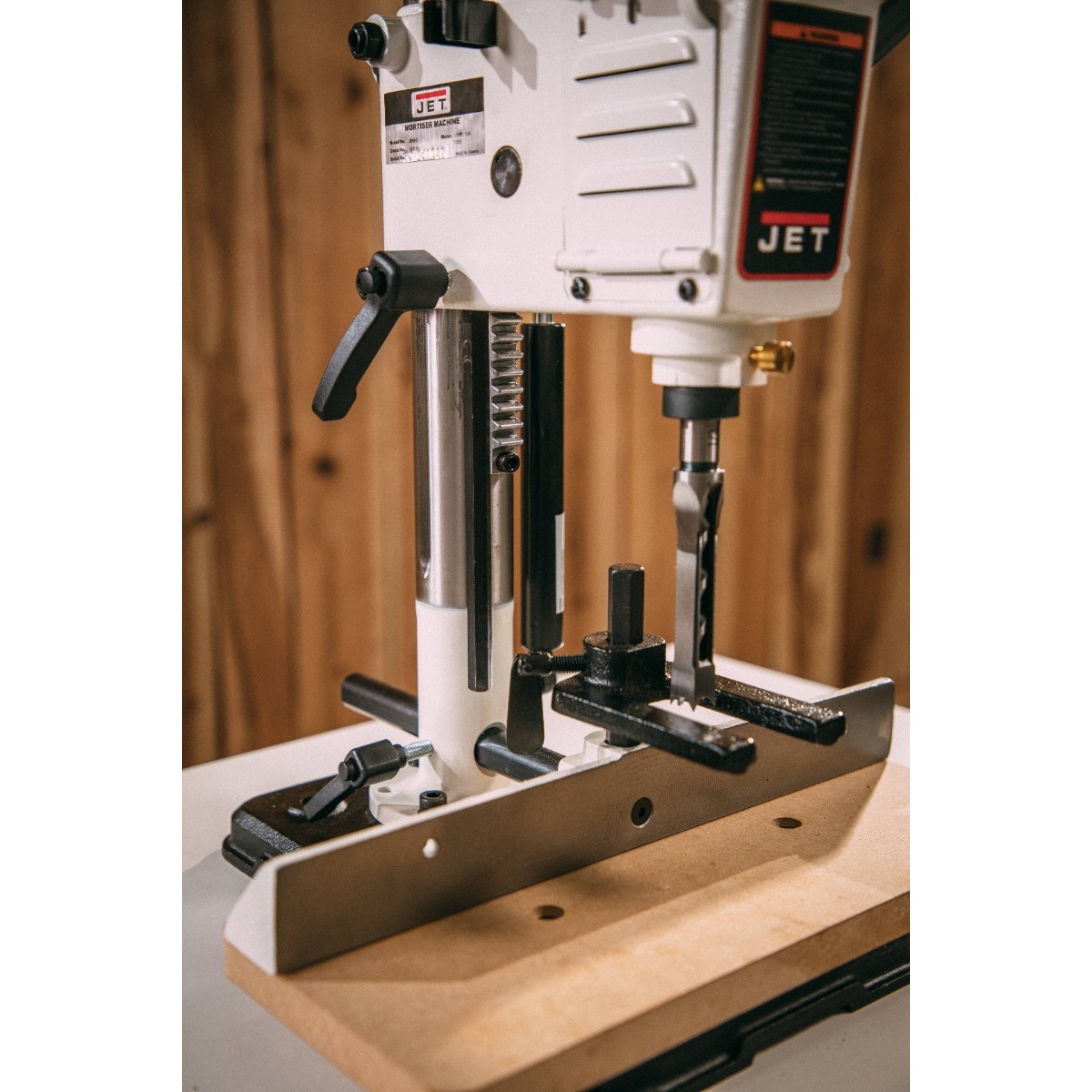 Jet benchtop mortiser cutting area with chisel and fence shown over wood stock on a bench, highlighting stable cast iron and steel construction for mortise-and-tenon work