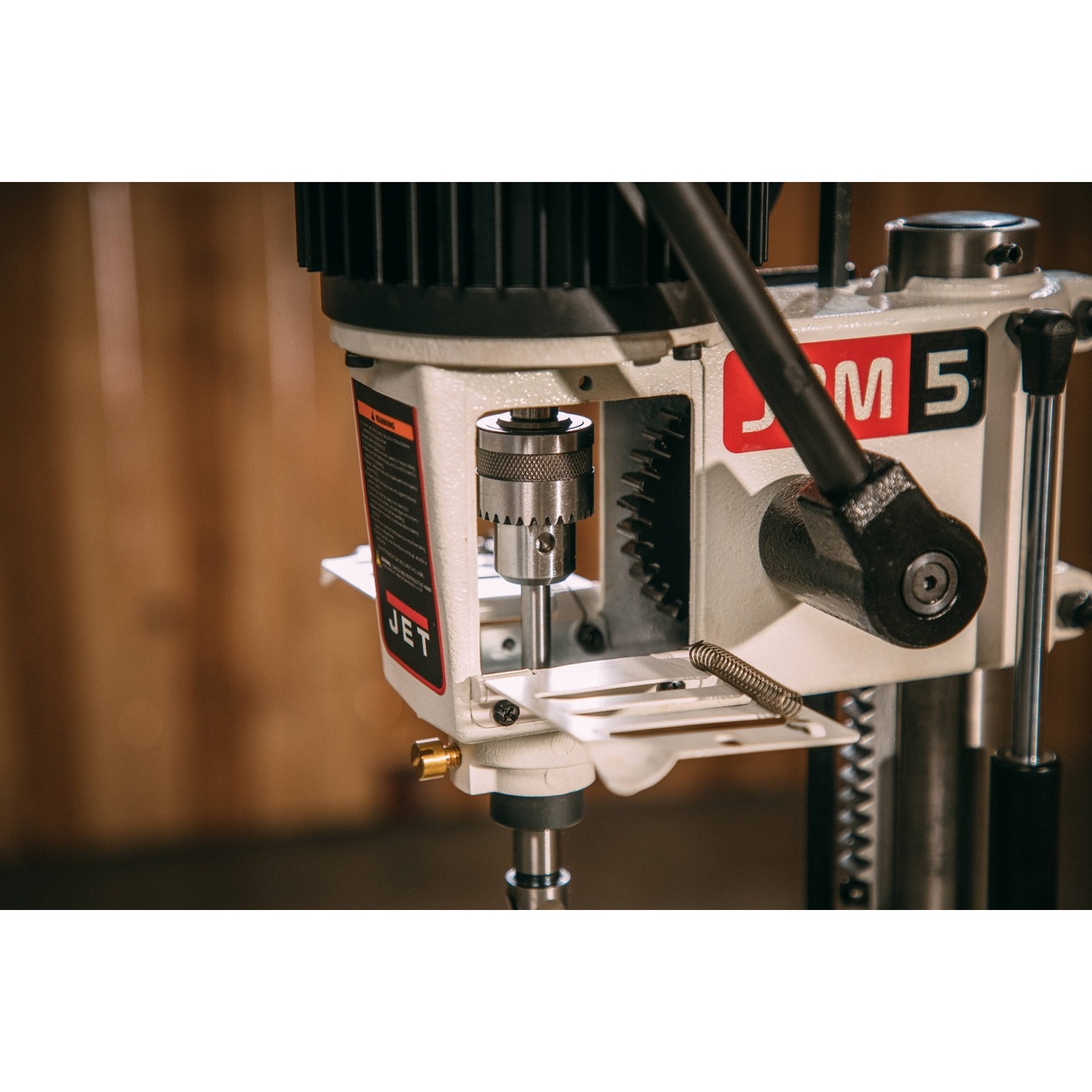 Close-up of the Jet 708580 Benchtop Mortise Machine drill chuck and hinged access door opened for quick mortising bit changes in a woodworking shop