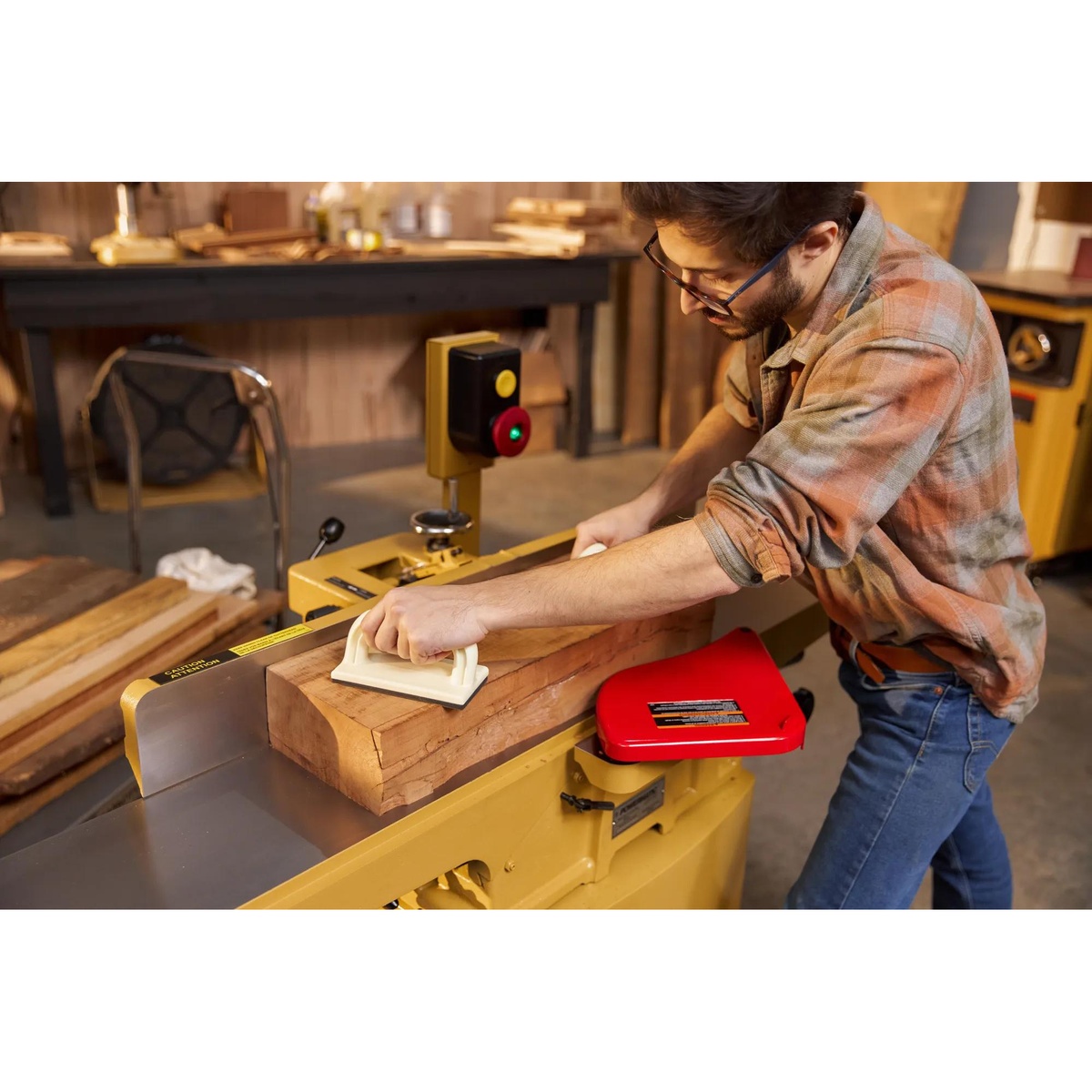 Powermatic 1610086K 60HH 8 inch jointer in use jointing a hardwood board in a woodworking shop with push blocks during face-jointing