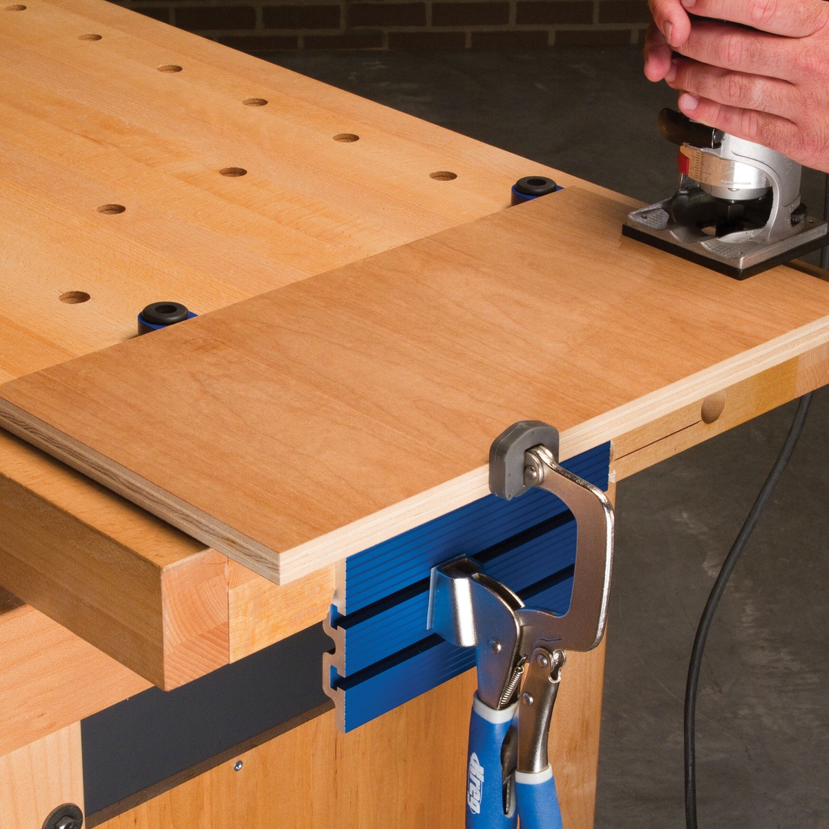 Kreg Bench Dogs and Bench Brakes (4-Pack) holding a plywood panel on a woodworking bench during router work in a real shop setup