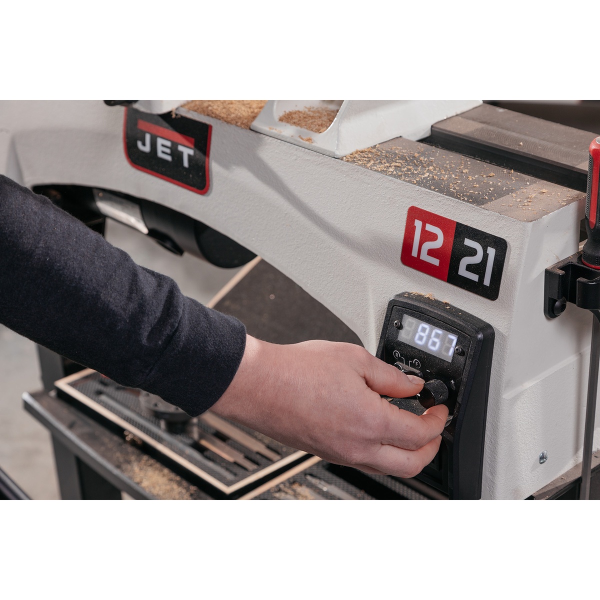 Jet 719200 JWL-1221VS 12 x 21 variable speed wood lathe control panel being adjusted in a woodworking shop while setting spindle speed for a turning job
