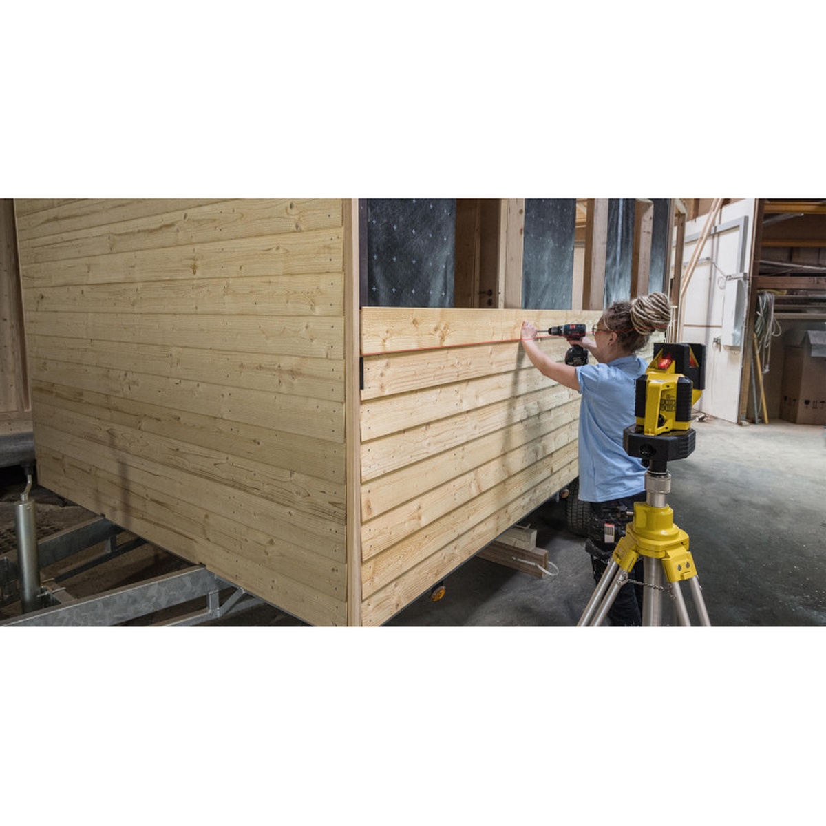 Stabila 02180 LA 180L Layout Laser Level Set projecting a red line for wall layout on wood framing while a user marks a level reference line