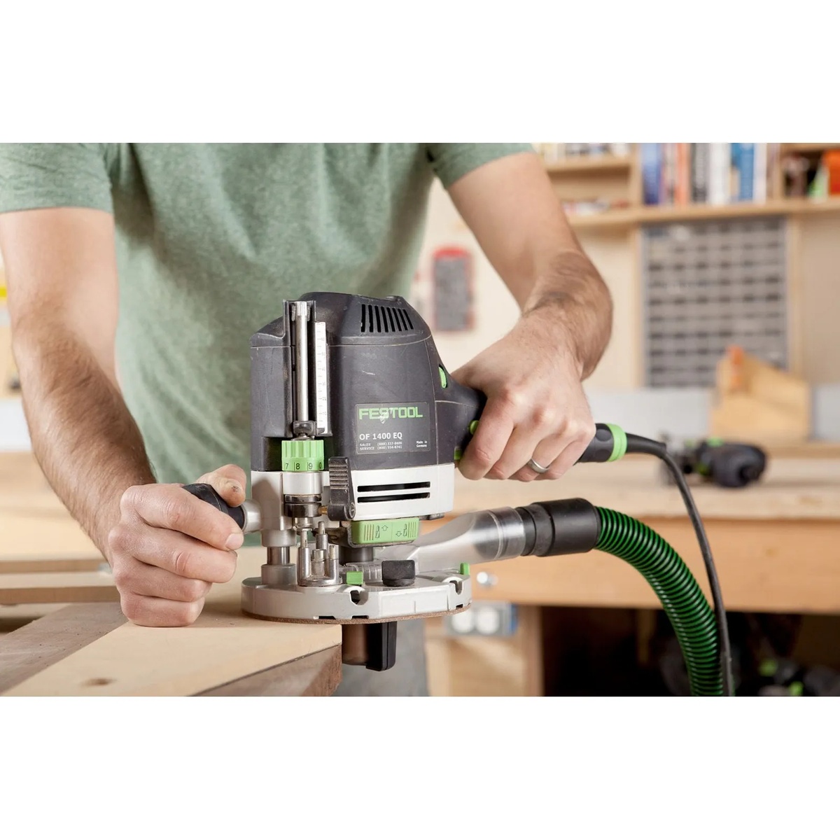 Festool OF 1400 EQ-F-Plus Plunge Router trimming the edge of a wood panel with the dust hose attached during bench routing