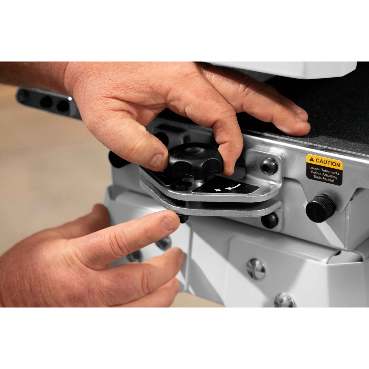 JET JWDS-1632 Drum Sander with Stand parallelism adjustment dial being set by hand on a woodworking machine for accurate panel sanding in a shop