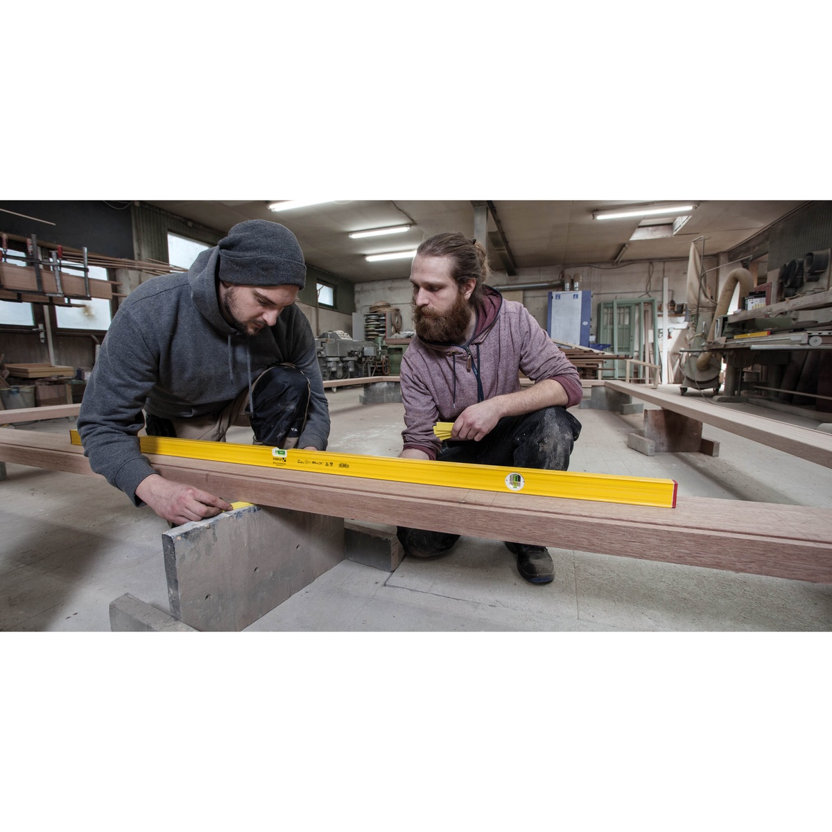 Stabila 29048 48 in. Type 80A-2 Non Magnetic Level checking a long wood workpiece in a workshop during carpentry layout