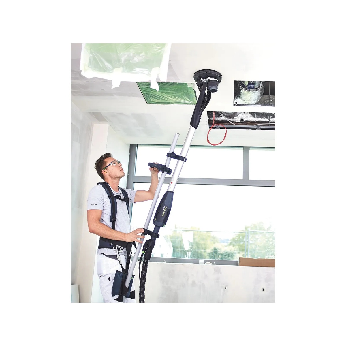 Festool 571935 Planex Easy Drywall Sander being used on a high ceiling in an interior construction space