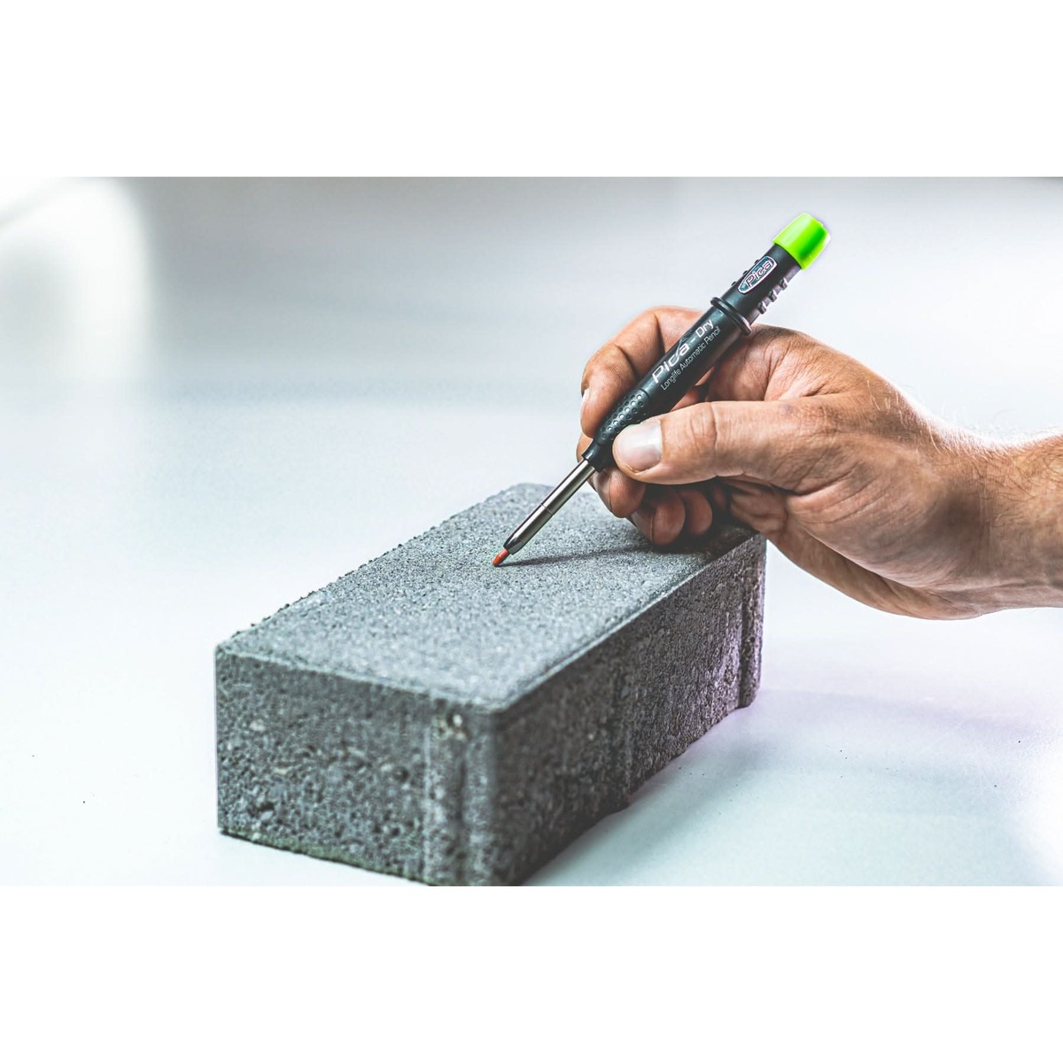 Pica Dry 3030 Pencil + 4030 Black Lead Refill making a layout mark on a rough concrete block in a shop setting