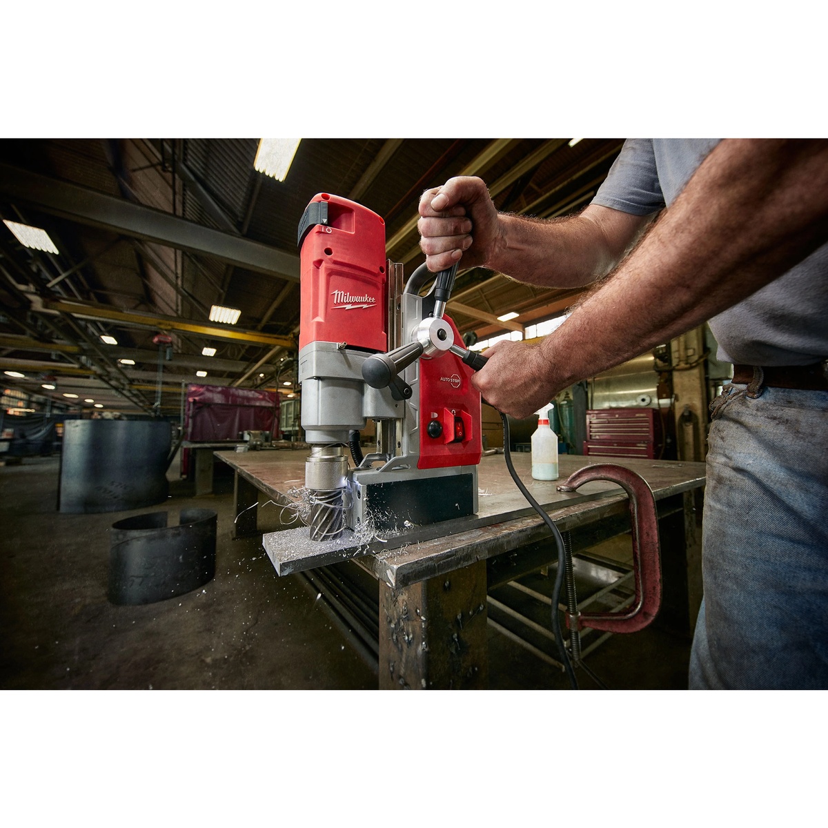 Milwaukee 4272-21 1-5/8 in. Electromagnetic Drill Kit drilling into a steel plate in a fabrication shop with metal chips forming during annular cutter drilling